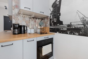A fully equipped kitchen with a stylish backsplash depicting historic industrial imagery.