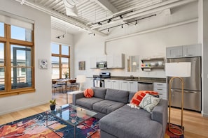 Funky and bright open-concept living/dining/kitchen area with lofted ceilings and a warm fireplace