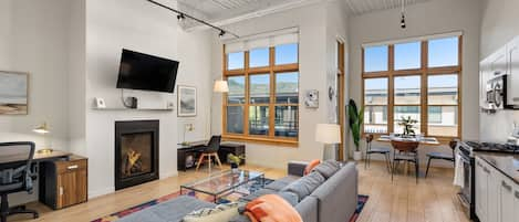 Funky and bright open-concept living/dining/kitchen area with lofted ceilings and a warm fireplace