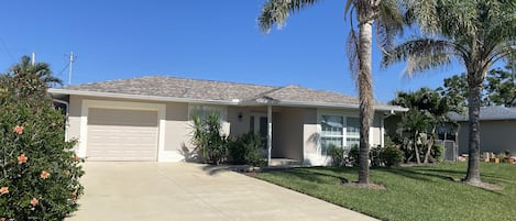 Front of House with beautiful landscaped yard and mature palm trees