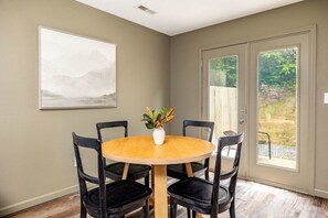 Our dining area is strategically placed in front of a sliding glass door, offering a stunning view of our backyard and the pathway to our relaxing hot tub.
