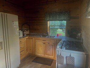 Kitchen with microwave, coffemaker, stove, sink, dishes, pans and utensils.