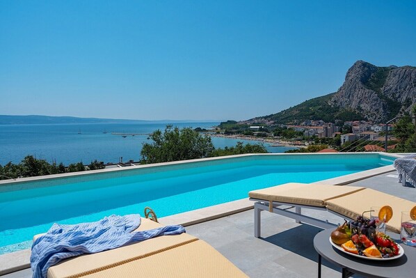 a sun deck area with 6 decks chairs overviewing town Omiš, sea and mountains