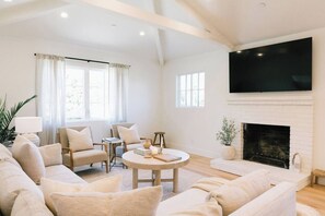 Living room has tons of light during the day, lots of seating, a fireplace, and a 65" TV