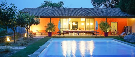 Le poolhouse et la piscine à la nuit tombante
