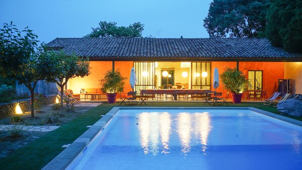 Le poolhouse et la piscine à la nuit tombante
