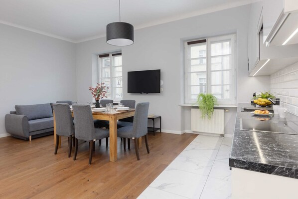 A spacious and bright living area featuring a gray sofa, wooden floors, and modern decor, creating a cozy and inviting atmosphere.