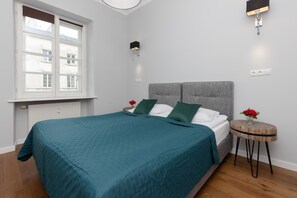 A bedroom with a comfortable bed dressed in a teal bedspread, bedside tables, and wall-mounted lighting for convenience.