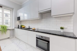 A fully equipped, modern kitchen with white cabinetry, a dark countertop, and a stylish subway tile backsplash.