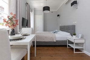 A view showcasing the open-plan layout with a bed, a seating area, and plenty of natural light coming through the windows.