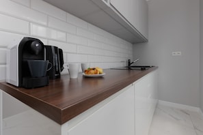 A well-equipped kitchenette with white cabinets, a dark wooden countertop, and a backsplash with white subway tiles.