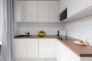 A sleek white kitchen with modern cabinets, black accents, and a functional layout, including a built-in microwave.