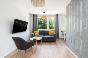 A cozy sitting area with a small round table, two gray chairs, and a TV mounted on the wall.

