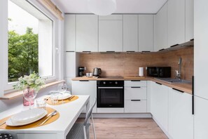 A bright, modern kitchen with white cabinetry, wooden countertops, and a breakfast setup.

