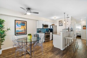 The dining area features a modern glass table with clear chairs, which helps maintain the open and airy feel of the space. The decor is cohesive with a mix of modern and eclectic elements, creating a unique and inviting ambiance.