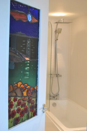 A bespoke stained-glass window leads to the bathroom