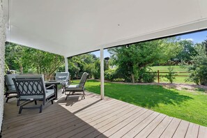 Shaded back porch with views of the park and firepit