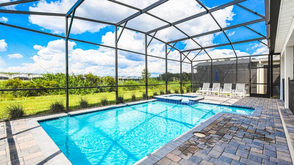 Relax in a screened private pool with spa and loungers, overlooking green views
