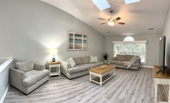 Spacious living room area with vaulted ceiling and sunny skylights!