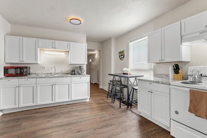 Spacious dine-in kitchen features ample cupboard and counterspace, dishes, cookery, pots, pans, silverware, cooking utensils, glassware, bakeware, fridge, microwave, toaster, coffee maker, tea kettle, knife set, and more! 