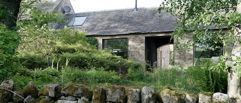 The Cartshed hidden in it's wild cottage garden