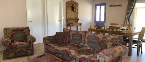 Open plan living space with settee and two chairs, dining table for 4 people.