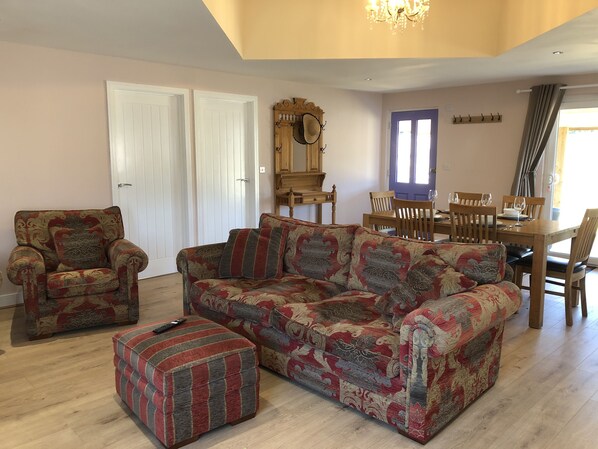 Open plan living space with settee and two chairs, dining table for 4 people.