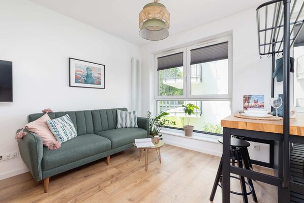 A cozy space featuring a sofa, large windows, and decorative lighting, creating a welcoming atmosphere.