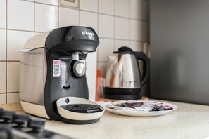 A close-up of a coffee machine on the kitchen counter, complemented by a kettle and cups for a warm welcome.
