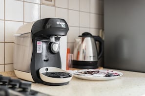 A close-up of a coffee machine on the kitchen counter, complemented by a kettle and cups for a warm welcome.