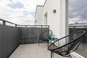 A spacious balcony with outdoor furniture and a view of the surrounding neighborhood.