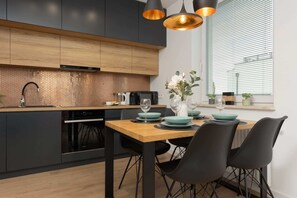 A modern kitchen with black cabinetry, wooden accents, and a dining table with gray chairs.