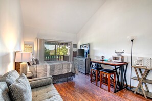 Cozy studio with queen bed, sofa bed, and outdoor patio view.