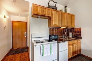 Cozy electric range, mini fridge, and warm wood kitchen cabinet.