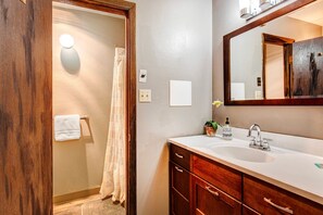 Gleaming sink, mirror, and shower under a warm overhead light.