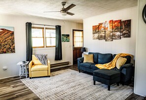 Cozy living room with comfortable seating, bright yellow chair, and artwork.
