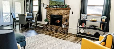 Cozy living room with a fireplace, bright decor, and a welcoming ambiance.