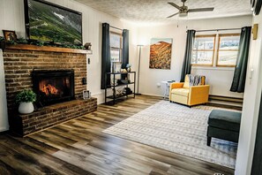 A cozy living room featuring a warm fireplace and a comfy yellow chair.