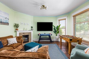 Get comfy in the living room with a plush couch, 75” Smart TV, foosball, and air hockey. Game night is on!