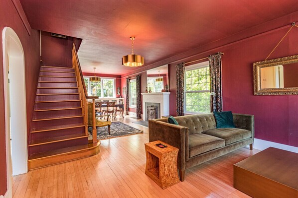 Enter into a large living/dining space with two velvet sofas, a seating area, and a carved dining table