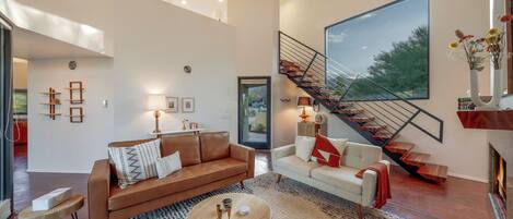 Beautiful living room with 25-ft ceilings, grand staircase, fireplace, and TV