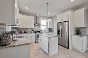 Modern, full size kitchen with ample cabinet and drawer space boasting fridge, freezer, kitchen island, Keurig, drip coffee maker, toaster, oven, stove and more!