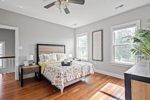 Secondary bedroom with queen-sized bed, ceiling fan, flat-screen Roku TV, natural lighting and walk-in closet.