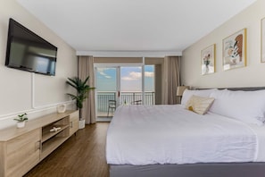 Wake up to breathtaking ocean views in this modern, serene bedroom featuring a plush king-size bed, stylish decor, and direct access to a private balcony. Relax in comfort with a flat-screen TV and soothing natural tones of the waves from the ocean.