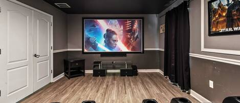 Dedicated movie theater equipped with plush seating, a large screen, creating an immersive cinematic experience