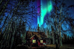 Cabin in the woods with the Northern lights in the sky. 