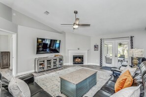 Open living room with leather furniture, LVP flooring, and large mounted flat screen tv