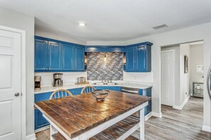 Open kitchen with stainless stain appliances, wooden island, and pantry