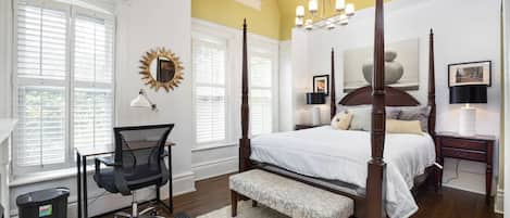 Large master bedroom with featuring high ceilings, a luxurious queen-size bed, a dedicated workstation and a en-suite master bathroom.