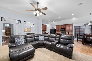 A leather sectional couch and view of the living room facing towards the kitchen and dining area.